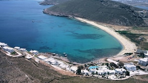 Oversigtsbillede af et kystområde med strand, bygninger og et bjergrigt bagland.