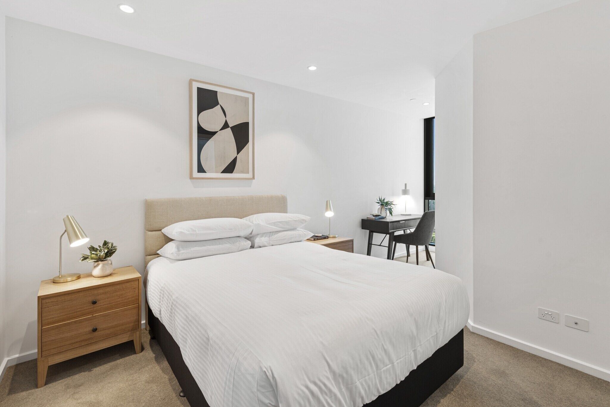 Um quarto moderno com uma cama grande, uma escrivaninha e uma cadeira.
