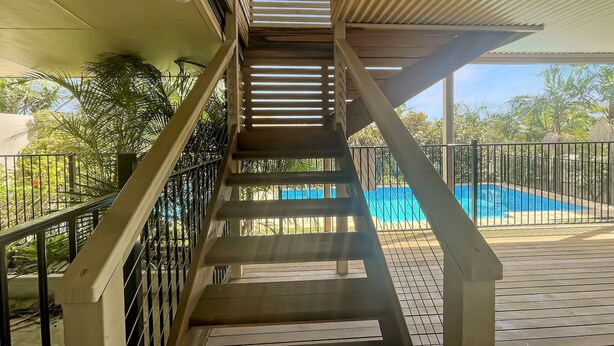 A wooden staircase with metal railings leading to a pool area. - Coastal Upper-Level Home with Pool Access (Batehaven)