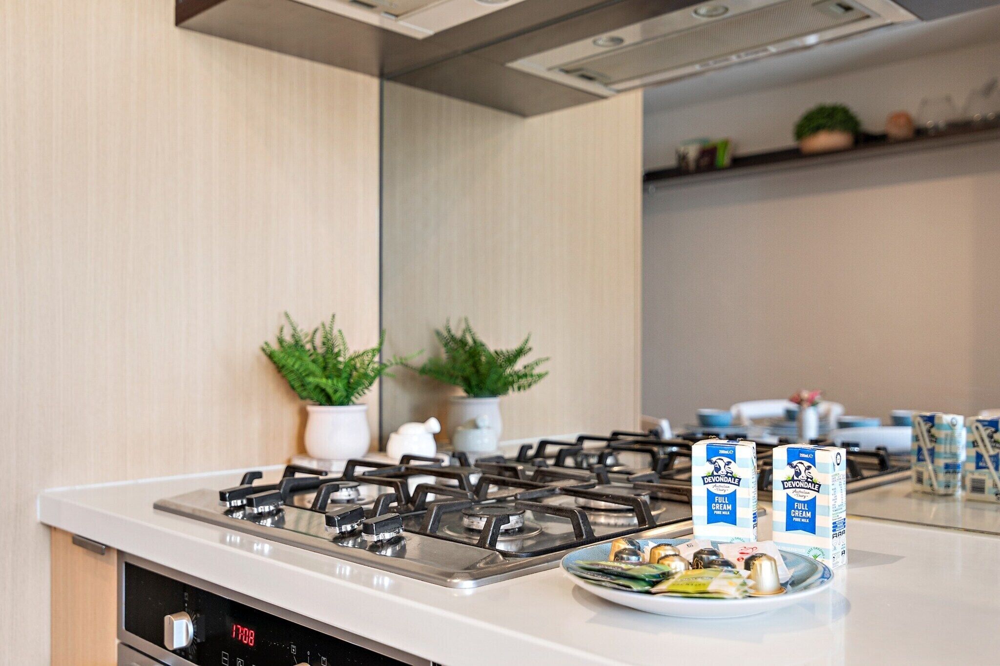 A modern kitchen with a gas stove, a digital clock, and a plate of food.