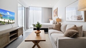 Una habitación de hotel moderna con una cama grande, un sofá, un televisor y un ventanal con cortinas.