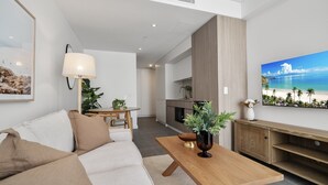 Una sala de estar moderna con un sofá, una mesa de centro y un cuadro de una playa.