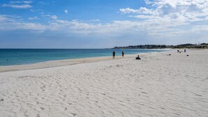 A wide sandy beach with a clear blue sky and calm sea. - Trendy 1-Bed Retreat in Fremantle with Rooftop (North Fremantle)
