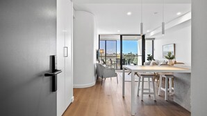 A modern kitchen with a dining area, large windows, and a view of the city. - Stylish 2-Bed Unit with Views & Rooftop Access (North Fremantle)