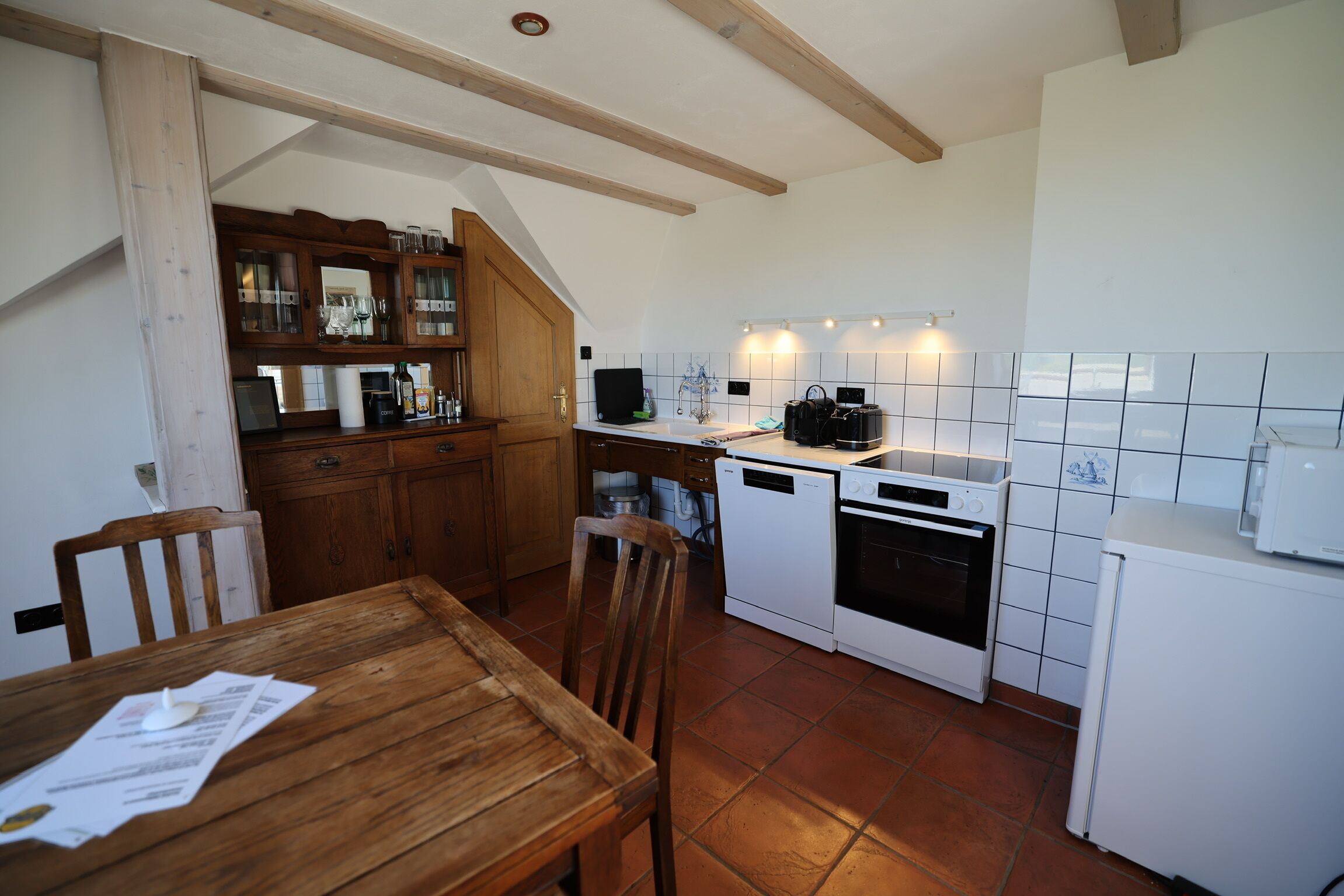 Una cucina con mobili in legno, un tavolo da pranzo ed elettrodomestici bianchi.