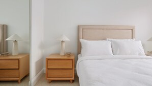 Un dormitorio con una cama, dos mesitas de noche y un espejo.