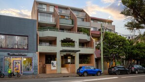 Un edificio de varios pisos con un gimnasio en la planta baja, un restaurante en el segundo piso y un estacionamiento al frente.