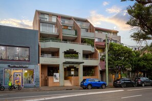 A multi-story building with a fitness center on the ground floor, a restaurant on the second floor, and a parking area in front. - Stylish 1-Bed Apartment Near Manly Beach (Manly)