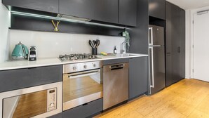 Una cucina moderna con mobili scuri, elettrodomestici in acciaio inossidabile e pavimento in legno.