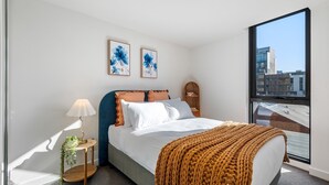 Una camera da letto moderna con un letto grande, un comodino con una lampada e due opere d'arte incorniciate al muro.