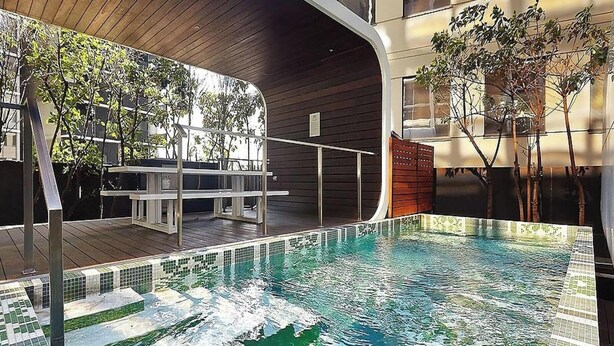 Una piscina interna moderna con un solarium in legno e un'area relax.