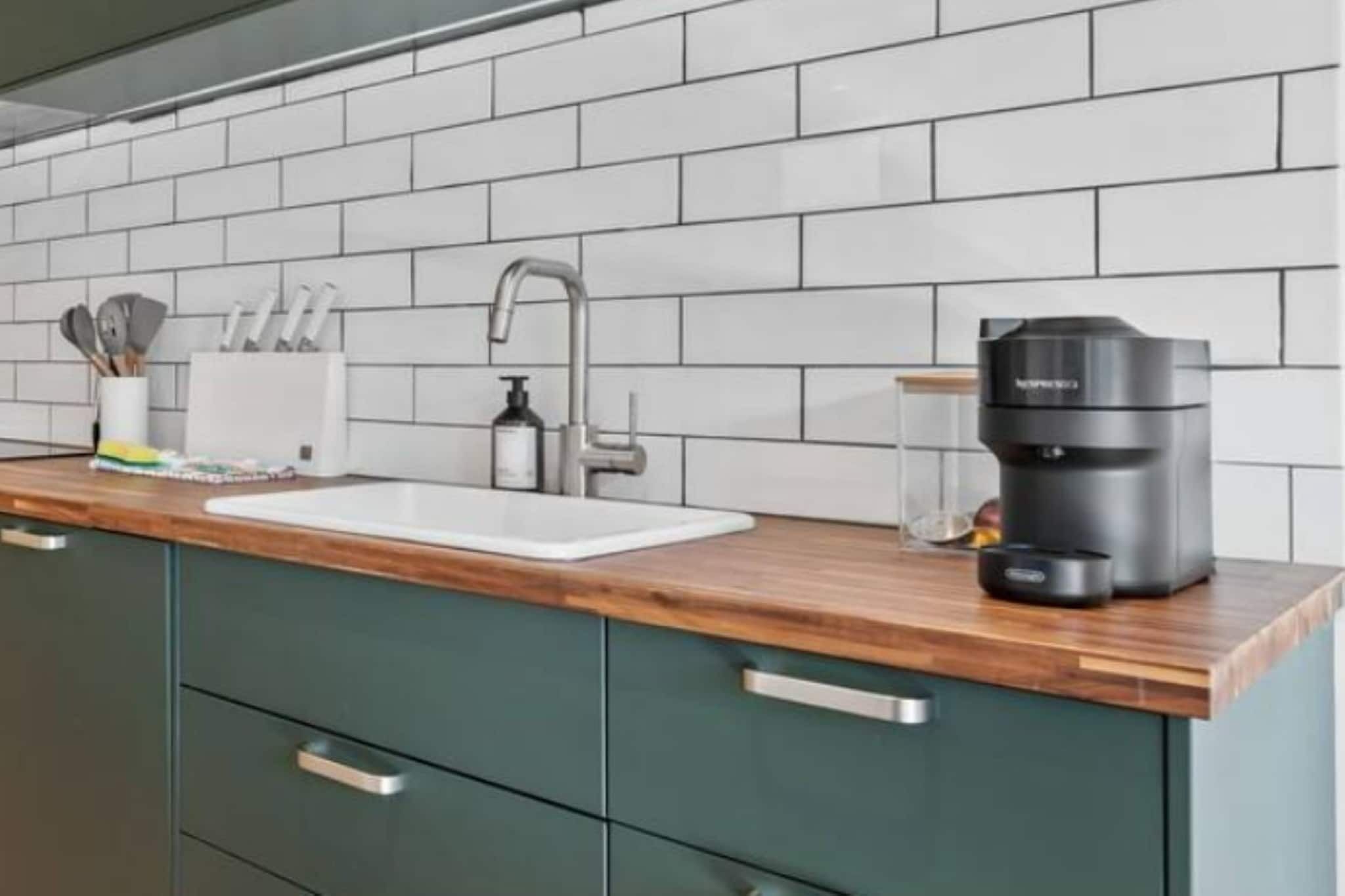 A kitchen with a white sink, a coffee maker, and a knife holder on the counter.