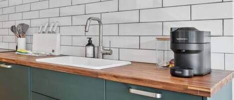 A kitchen with a white sink, a coffee maker, and a knife holder on the counter.