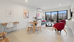 Un salon moderne comprenant un coin repas, un ensemble de canapés et une cloison en verre.