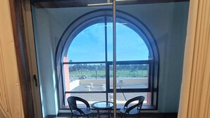 A room with a large arched window, a sliding glass door, and a small table with two chairs.