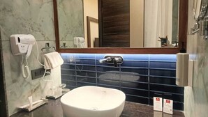 A bathroom with a white sink, a mirror, a towel dispenser, and a phone.