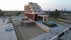 A modern building with a multi-level structure, a parking area with several cars, and a landscaped garden area.