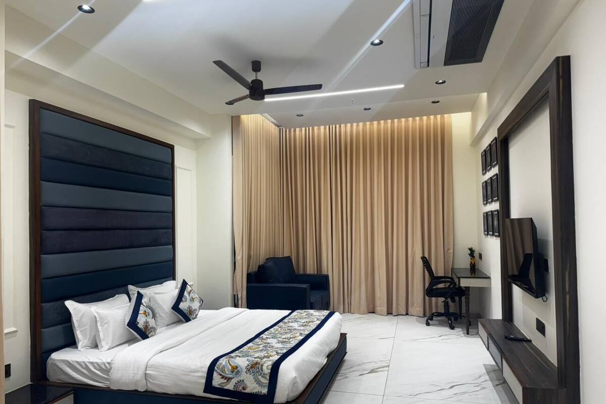 Un dormitorio moderno con una cama grande, un escritorio, una silla y un televisor en la pared.