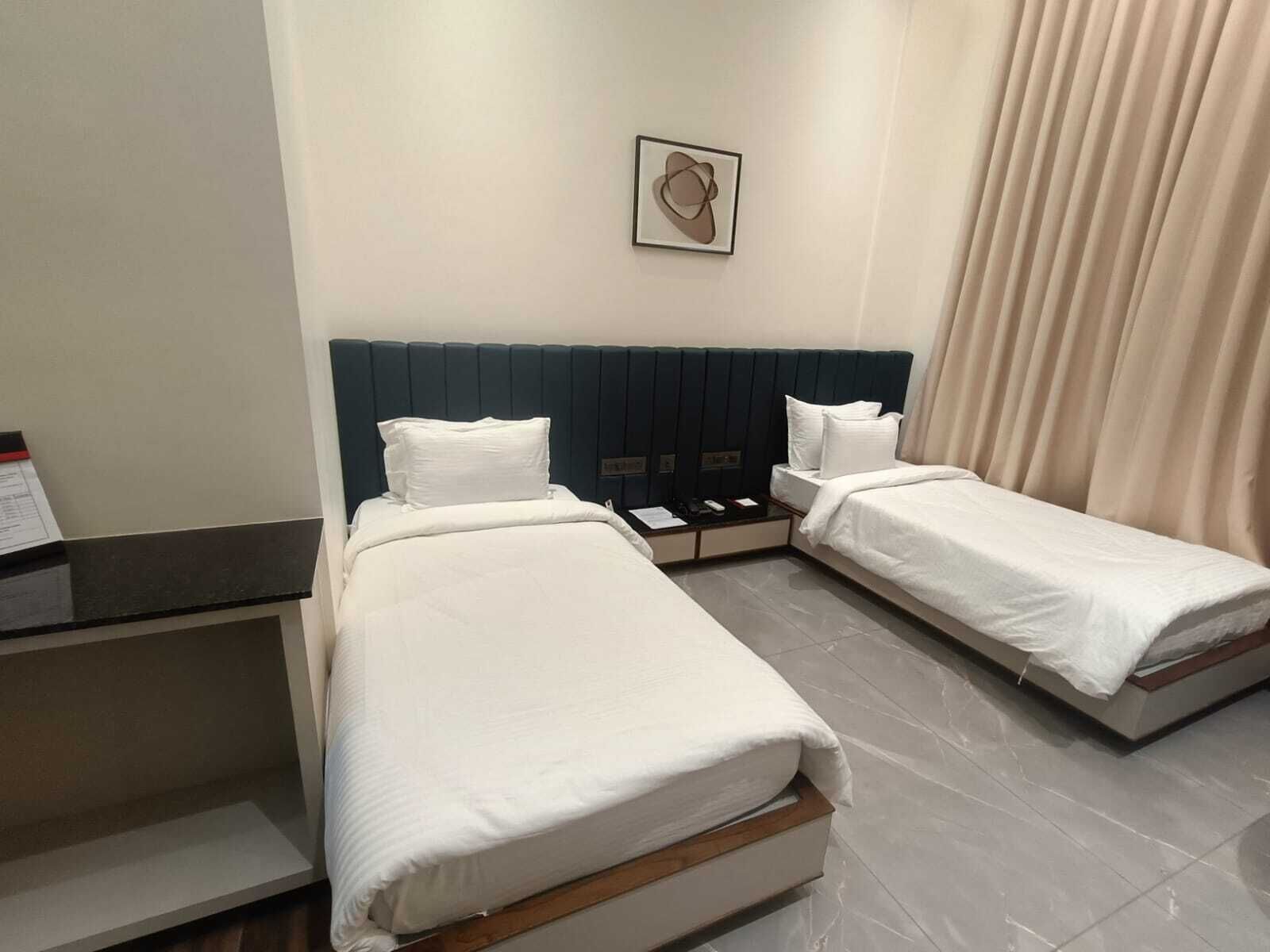 Une chambre d’hôtel avec deux lits, une table de chevet, une petite table et une œuvre d’art accrochée au mur.