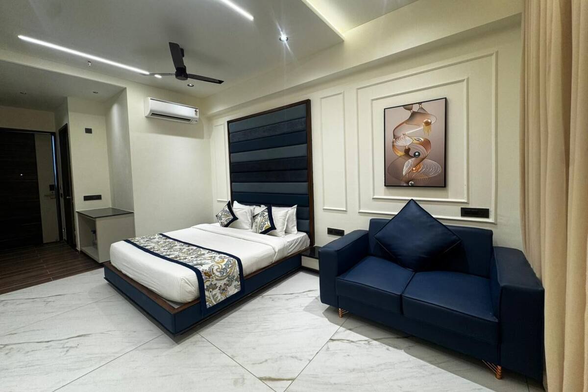 Un dormitorio moderno con cama, sofá, aire acondicionado y ventilador de techo.