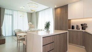 A modern kitchen with a central island, wooden cabinets, and a dining area with a table and chairs. - Experience 2BR Luxury Living  LIV Marina (Dubai)