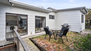 Ein modernes Haus mit Terrasse, Sitzgelegenheiten im Freien und einem Grillbereich.