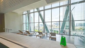 A modern indoor area with large windows, a pool, and lounge chairs. - Elegant Southbank Escape Apartment with Balcony (Southbank)