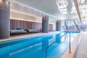 Ein moderner, überdachter Pool mit freiem Blick auf die Stadtkulisse durch große Fenster.
