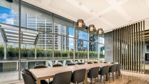 A modern conference room with a long table, black chairs, and large windows offering a city view. - Elegant Southbank Escape Apartment with Balcony (Southbank)