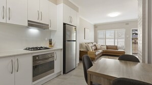 A modern kitchen with white cabinets, stainless steel appliances, and a dining area with a wooden table and chairs.