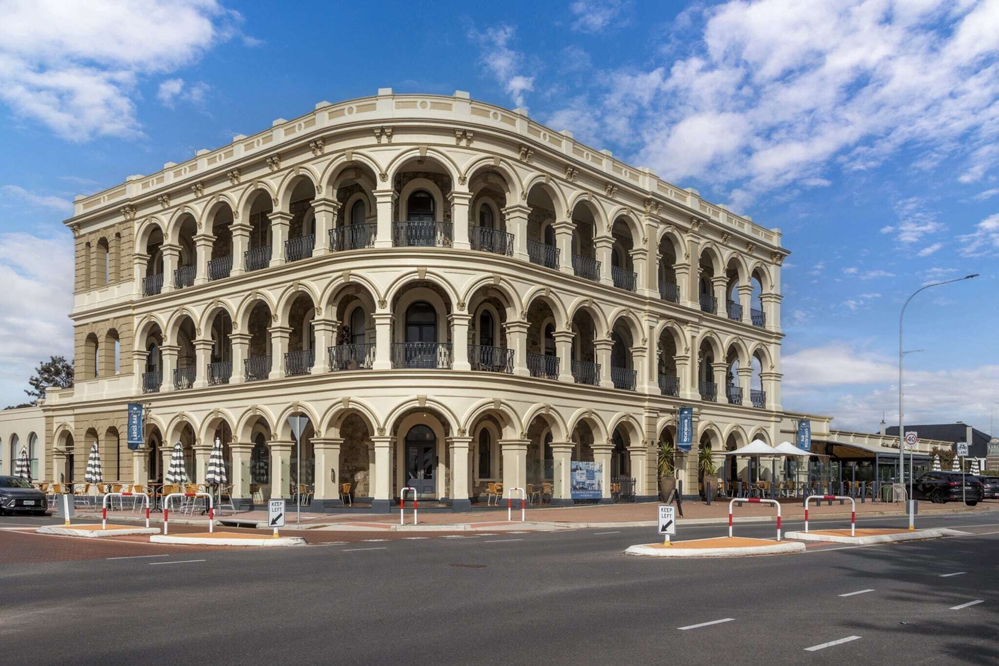 Edifici històric amb múltiples arcs i balcons, situat en una cantonada de carrer sota un cel clar.