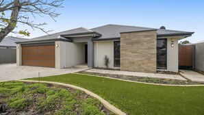 A modern two-story house with a garage, a well-maintained lawn, and a small tree in the front yard. - Spacious 4-Bed House with Outdoor Area (Byford)