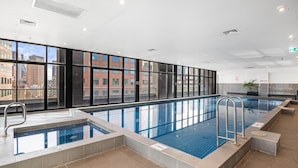 Ein Hallenbad mit freiem Blick auf die Stadt durch große Fenster.