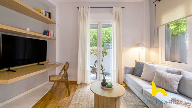 Una sala de estar moderna con un televisor de pantalla plana, estanterías de madera, un sofá y una mesa de centro.