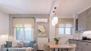 Una sala moderna con sofá, una mesa de comedor y una cocina con armarios y ventana.