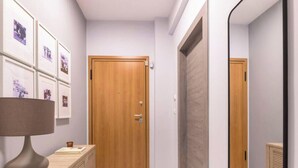 Un pasillo con una puerta de madera, un espejo y cuadros en la pared.