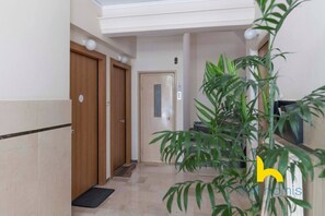 A hallway with wooden doors, a tiled floor, and a potted plant. - Sun-Splashed Sanctum w/ Green Patio, Acropolis (Athens)