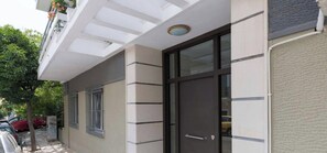 A building with a large glass door, a barred window, and a white facade with horizontal lines. - Sun-Splashed Sanctum w/ Green Patio, Acropolis (Athens)