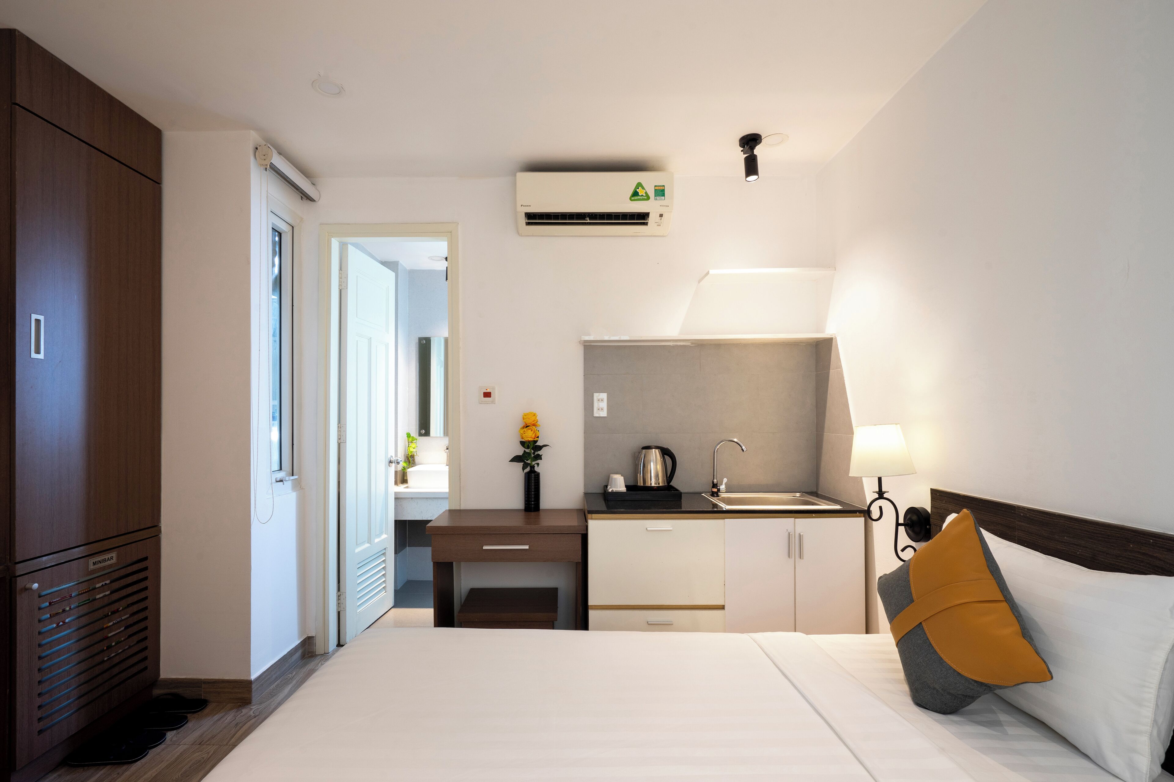 Hotellihuone, jossa on sänky, työpöytä, pieni keittiö ja vaatekaappi.