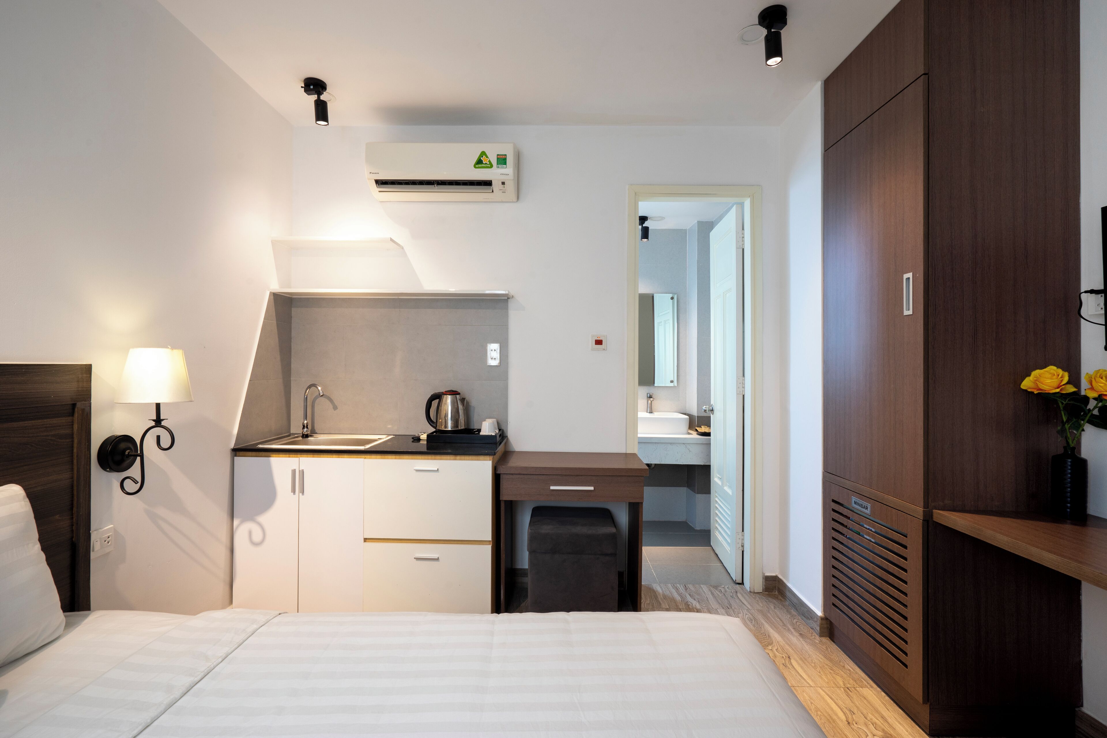 Una camera d'albergo con un letto, una scrivania con un lavandino, uno specchio e un armadio.