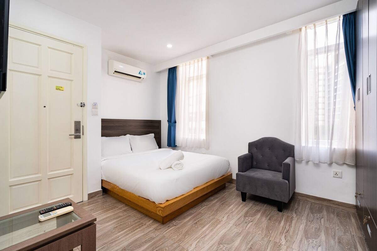 Una habitación de hotel con cama, una silla, televisión y aire acondicionado.