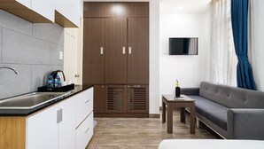 Una cocina moderna con estufa integrada, un comedor con mesa y sillas, y una sala de estar con sofá y televisor.