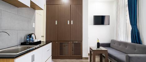 A modern kitchen with a built-in stove, a dining area with a table and chairs, and a living area with a sofa and a TV.