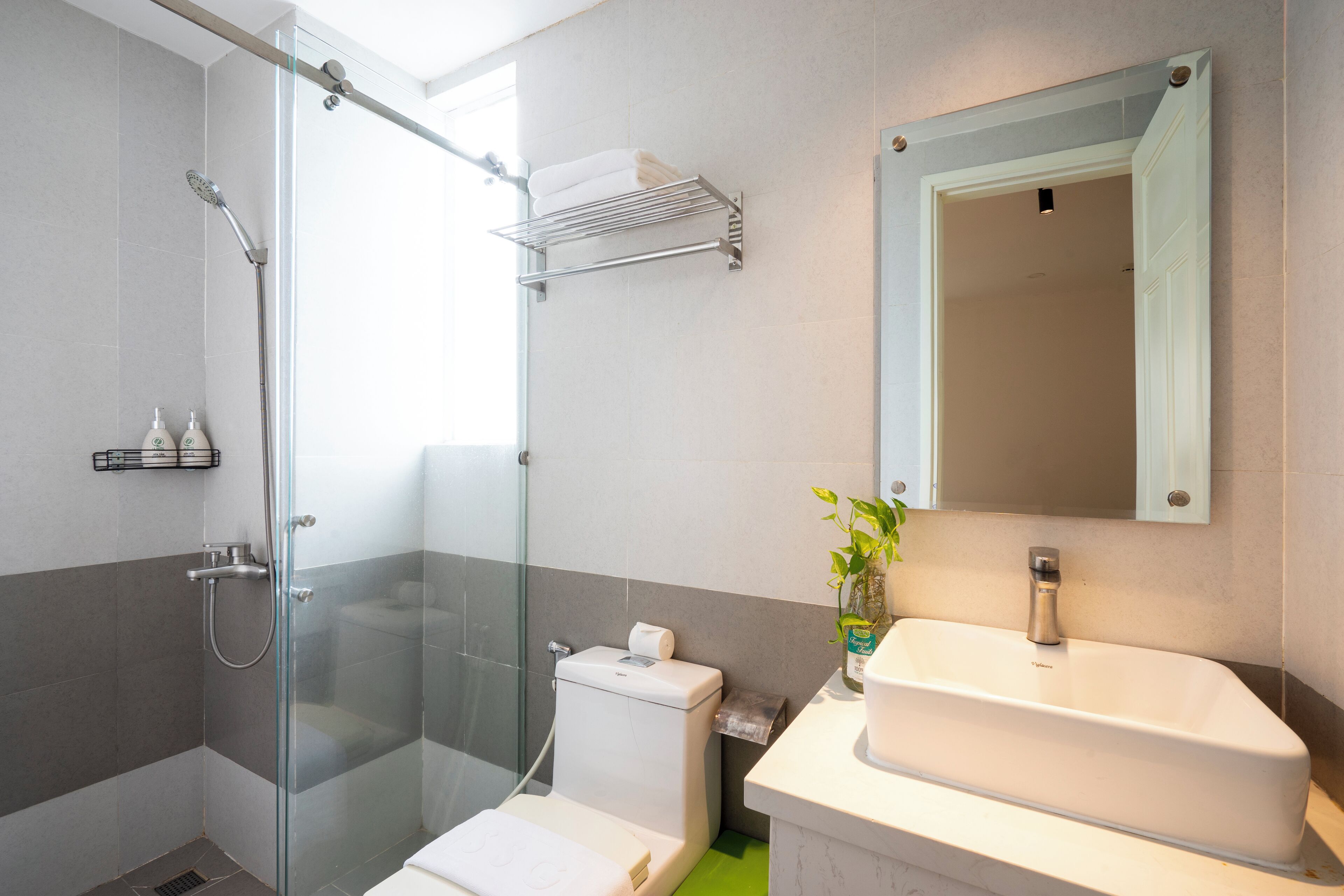 A modern bathroom with a glass shower enclosure, a white sink, and a mirror above the sink.