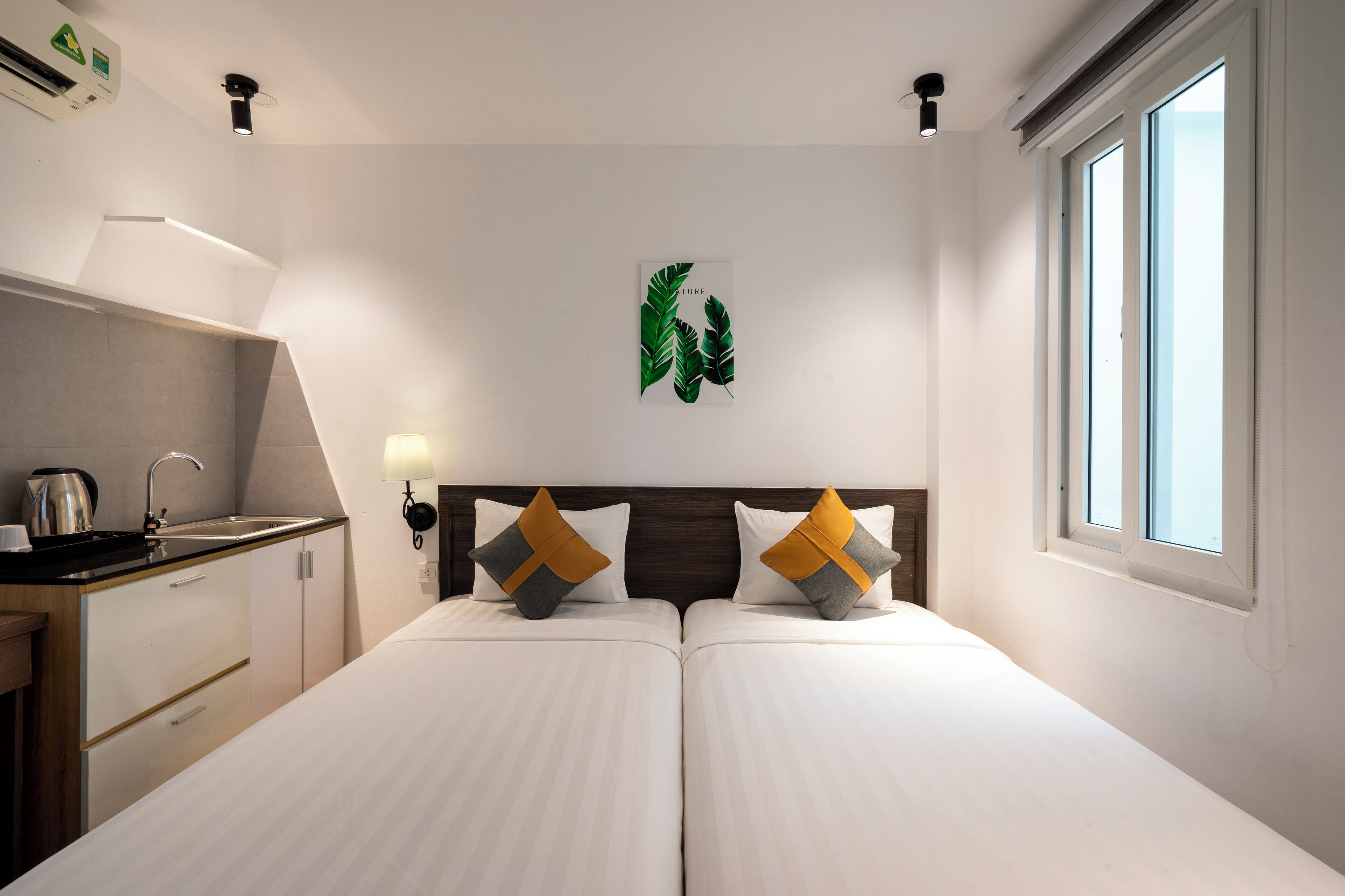 Una camera d'albergo con un letto, un angolo cottura, una finestra e un'opera d'arte appesa al muro.