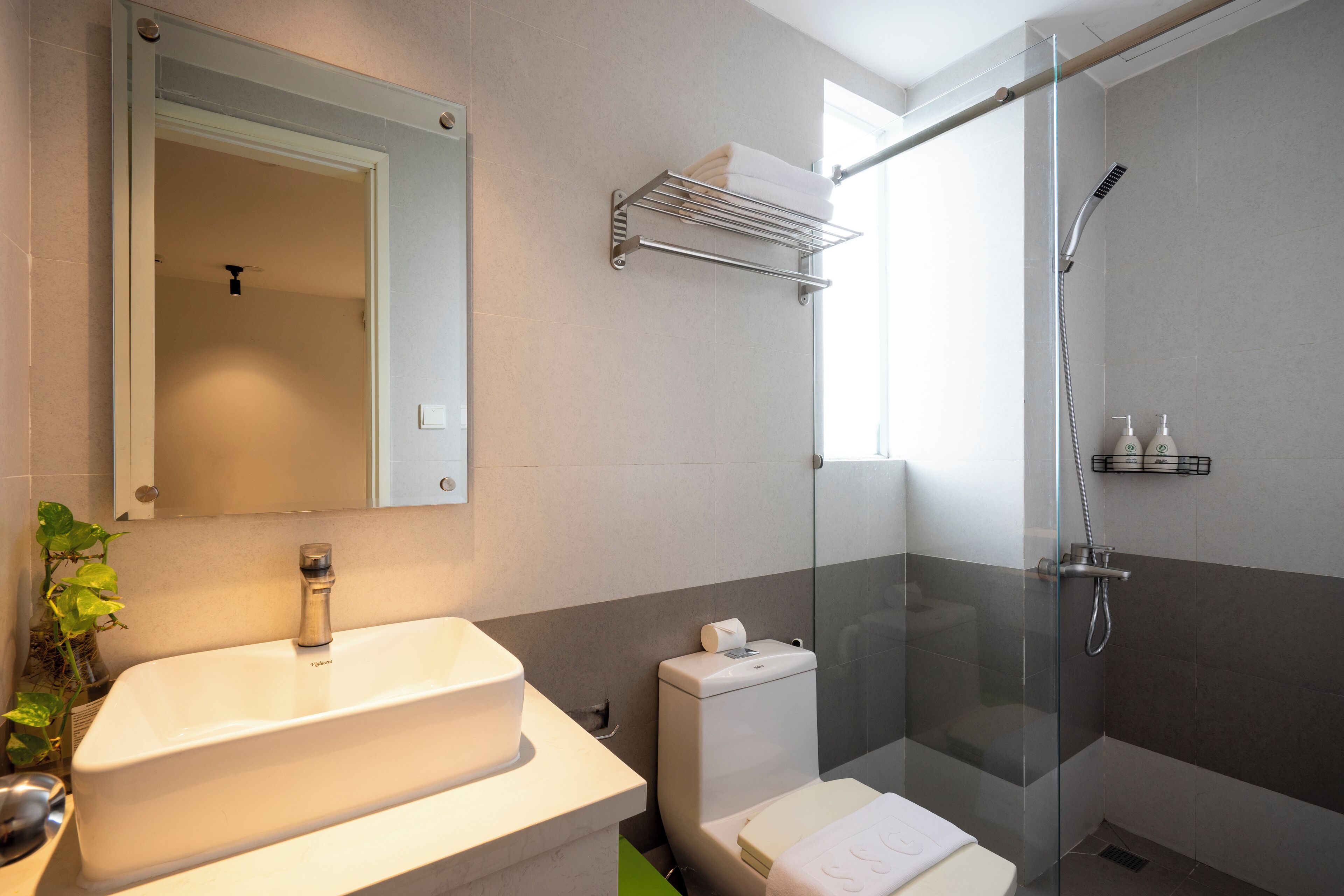 Un baño moderno con un lavamanos grande, inodoro y ducha con cerramiento de vidrio.
