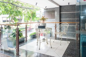 A glass-walled indoor area with metal furniture, a potted plant, and a view of the street outside. - Sonder - Tan Son Nhat Airport Hotel (Ho Chi Minh City)