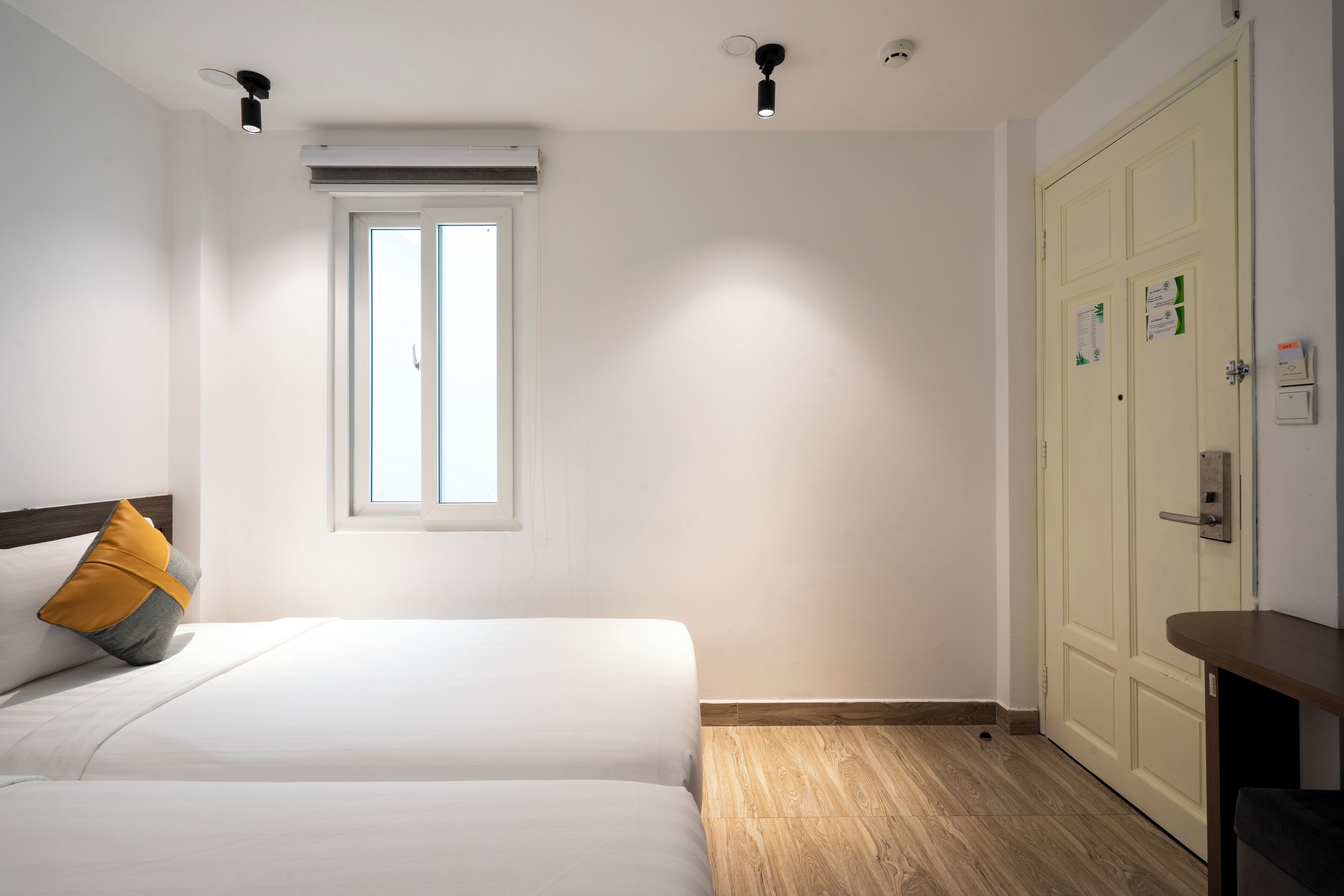 A hotel room with a bed, a window, a wardrobe, and a desk.
