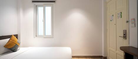A hotel room with a bed, a window, a wardrobe, and a desk.