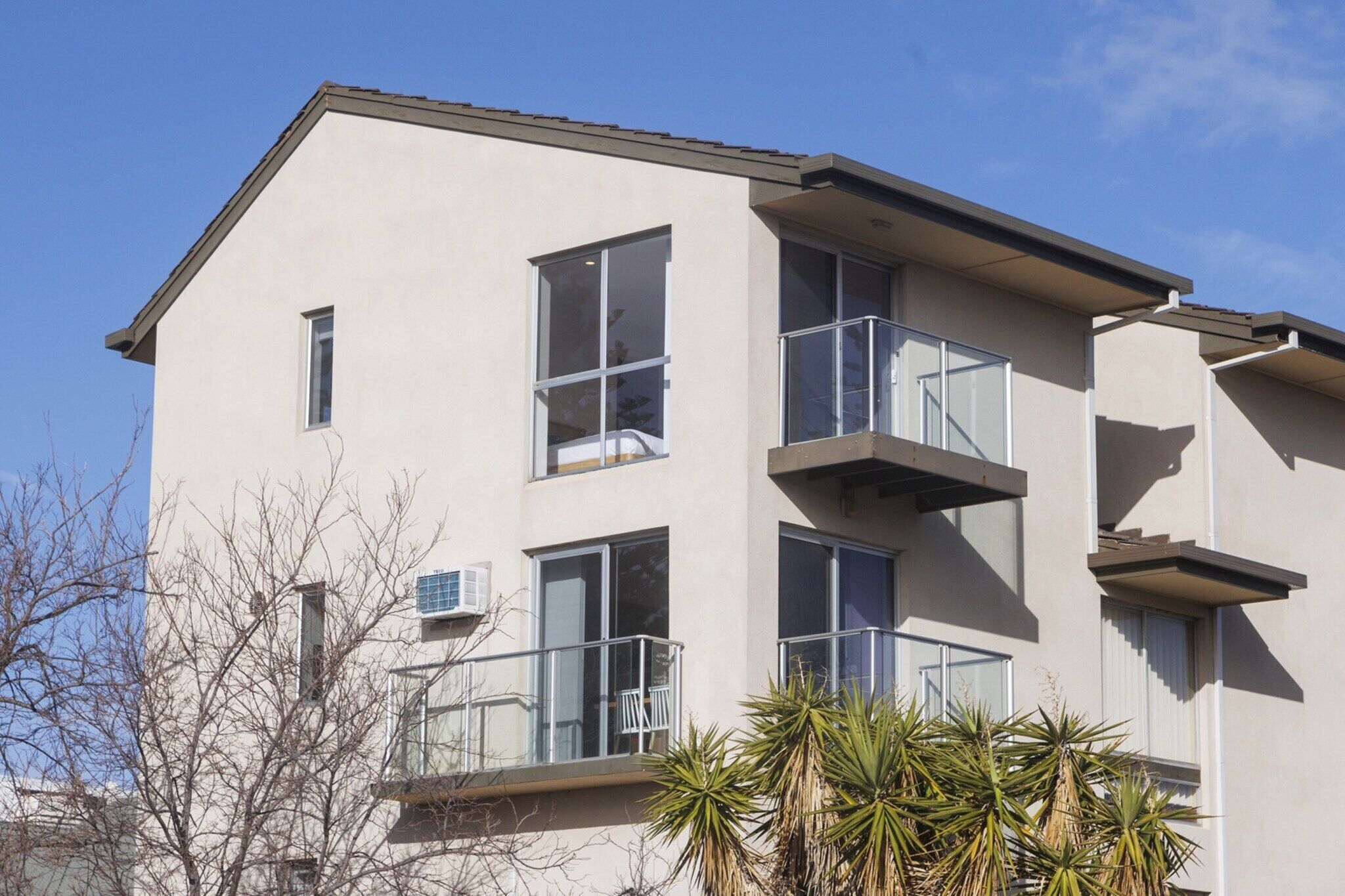 A multi-story building with balconies, large windows, and a flat roof.